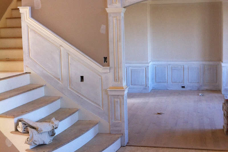 At the top of this staircase the wainscoting panel goes vertical and the top cap molding is mitered to match the elevation of the panel on the other side of this corner.